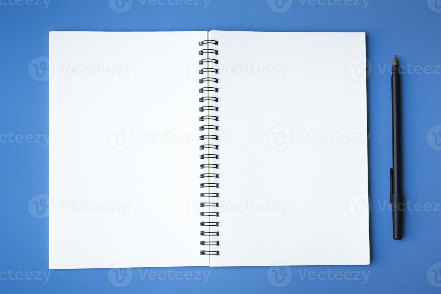 Top view of pen and notepad on blue background. Copy space. photo