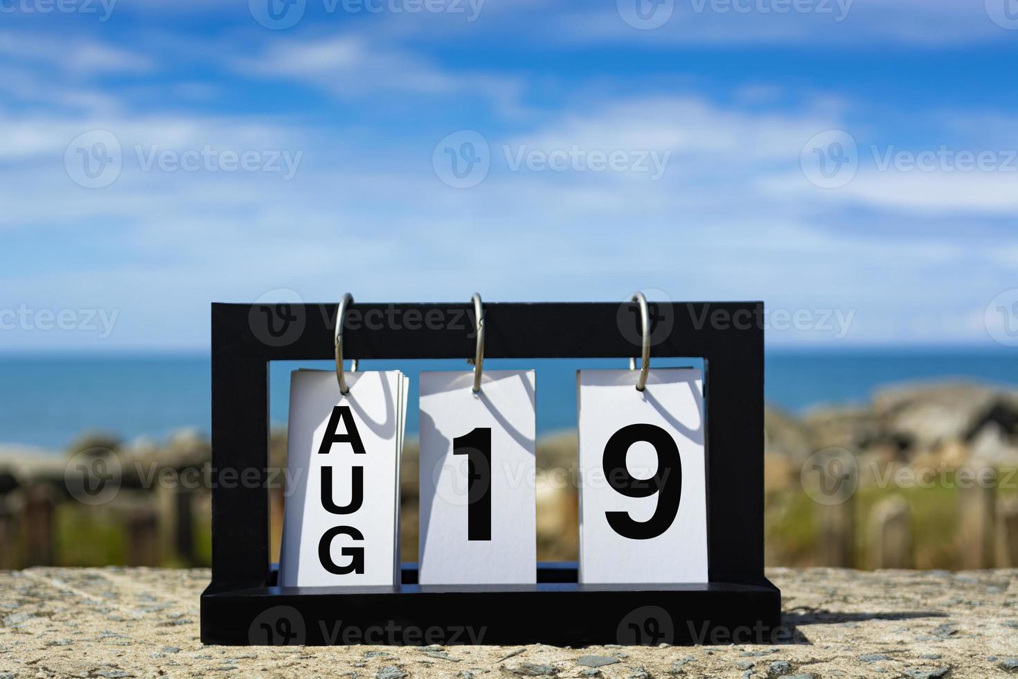 Aug 19 calendar date text on wooden frame with blurred background of ocean. photo