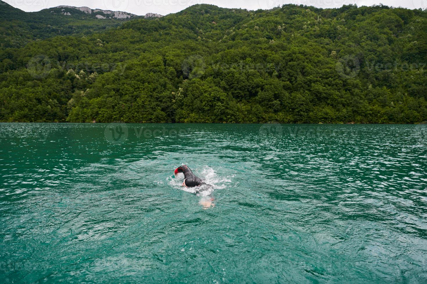 triathlon athlete swimming on lake wearing wetsuit photo