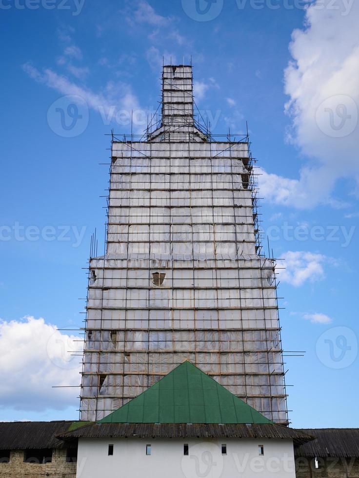 Scaffolding from planks around old bell tower. Concept of historical reenactment of repair work, access to elements of buildings of complex configuration. photo