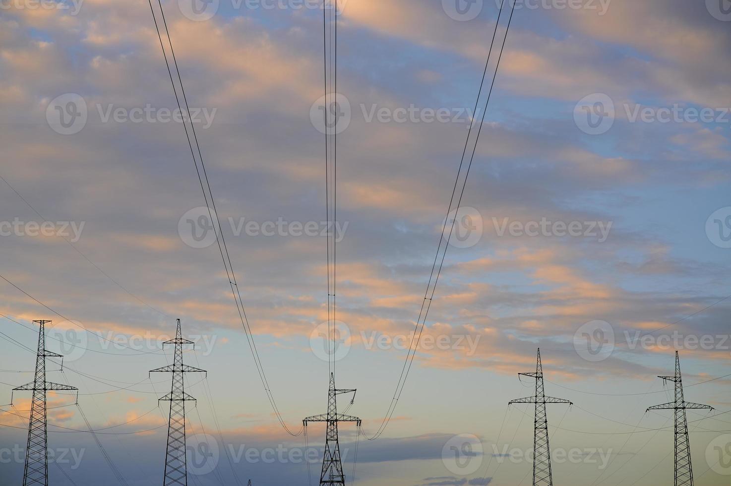 High voltage power lines with electricity pylons against the background of the evening cloudy sky. photo