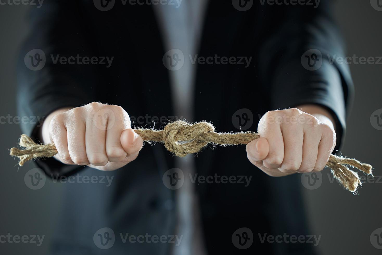 The businessman's hands tighten the rope knot against background of suit in blur. photo