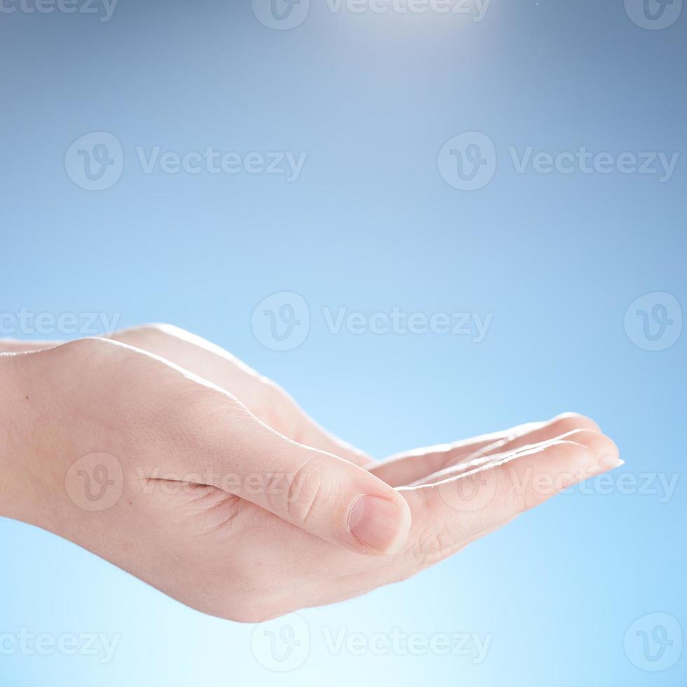 Close-up of beautiful woman's hands, palms up. Isolated on blue background. Photo from copy space.