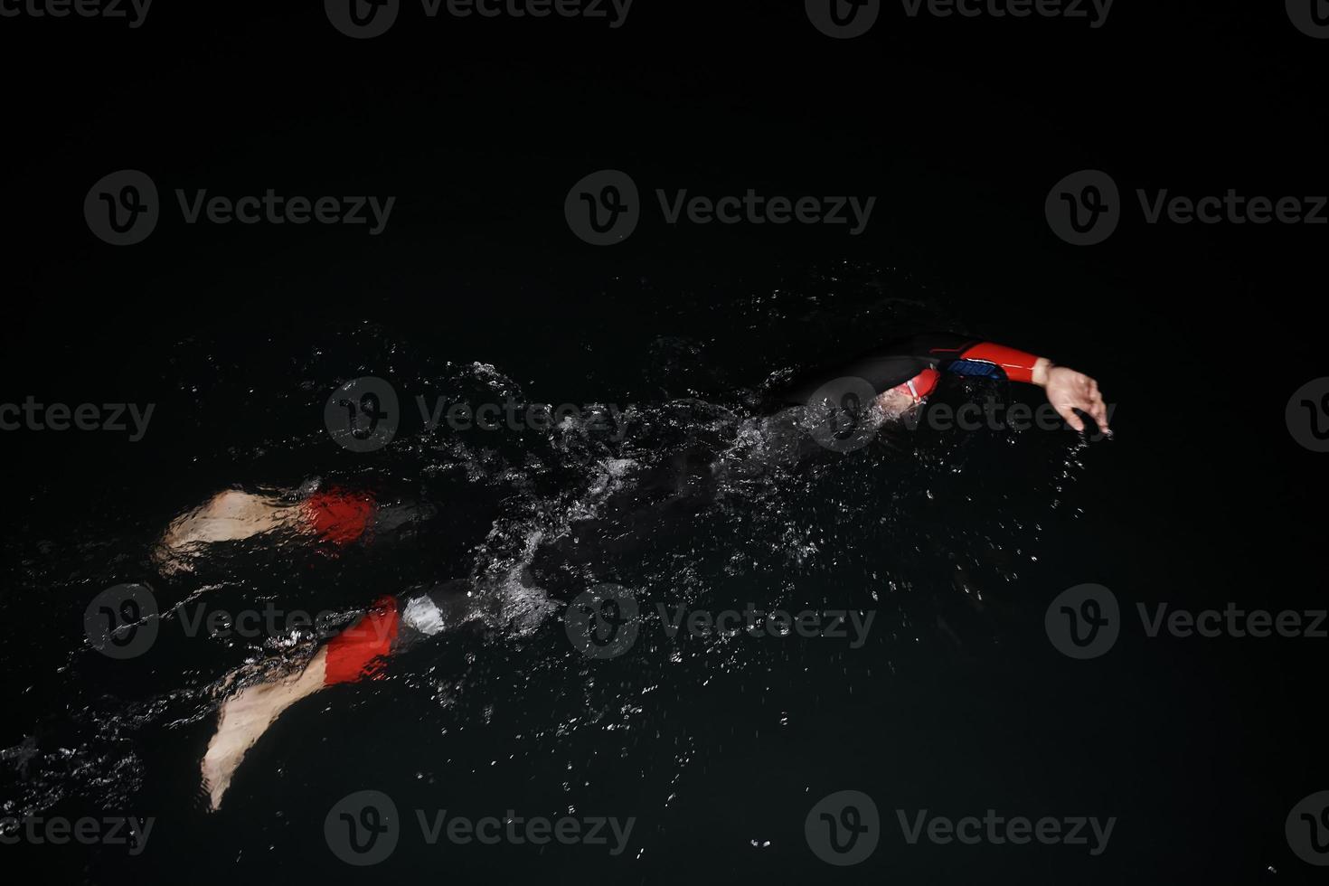 atleta de triatlón nadando en la noche oscura con traje de neopreno foto