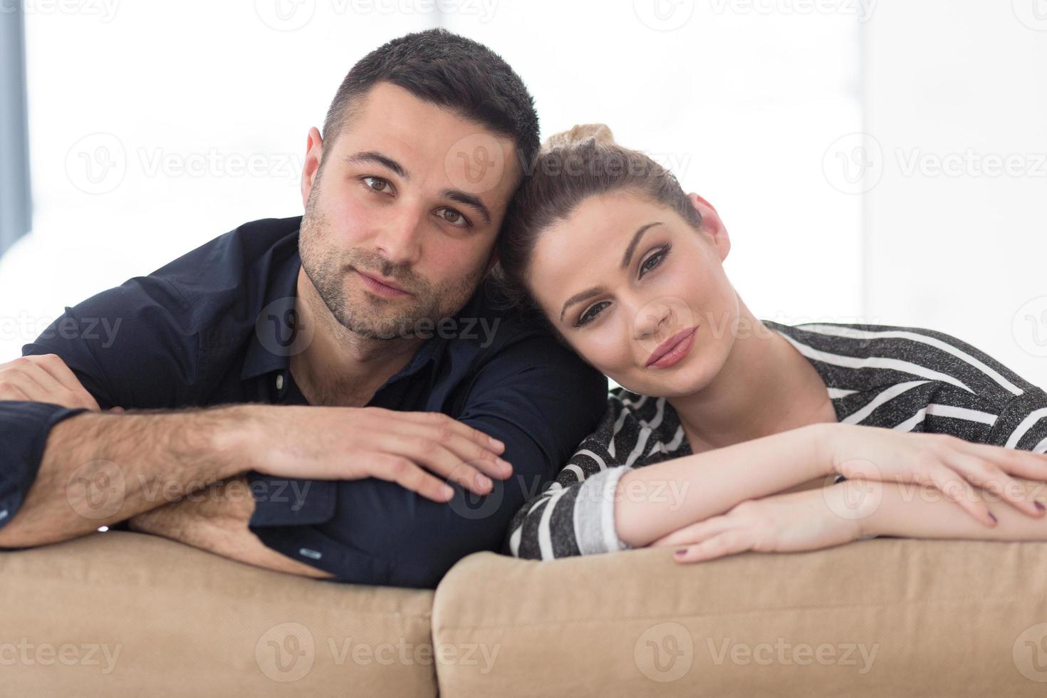 Portrait of young couple sitting on sofa photo