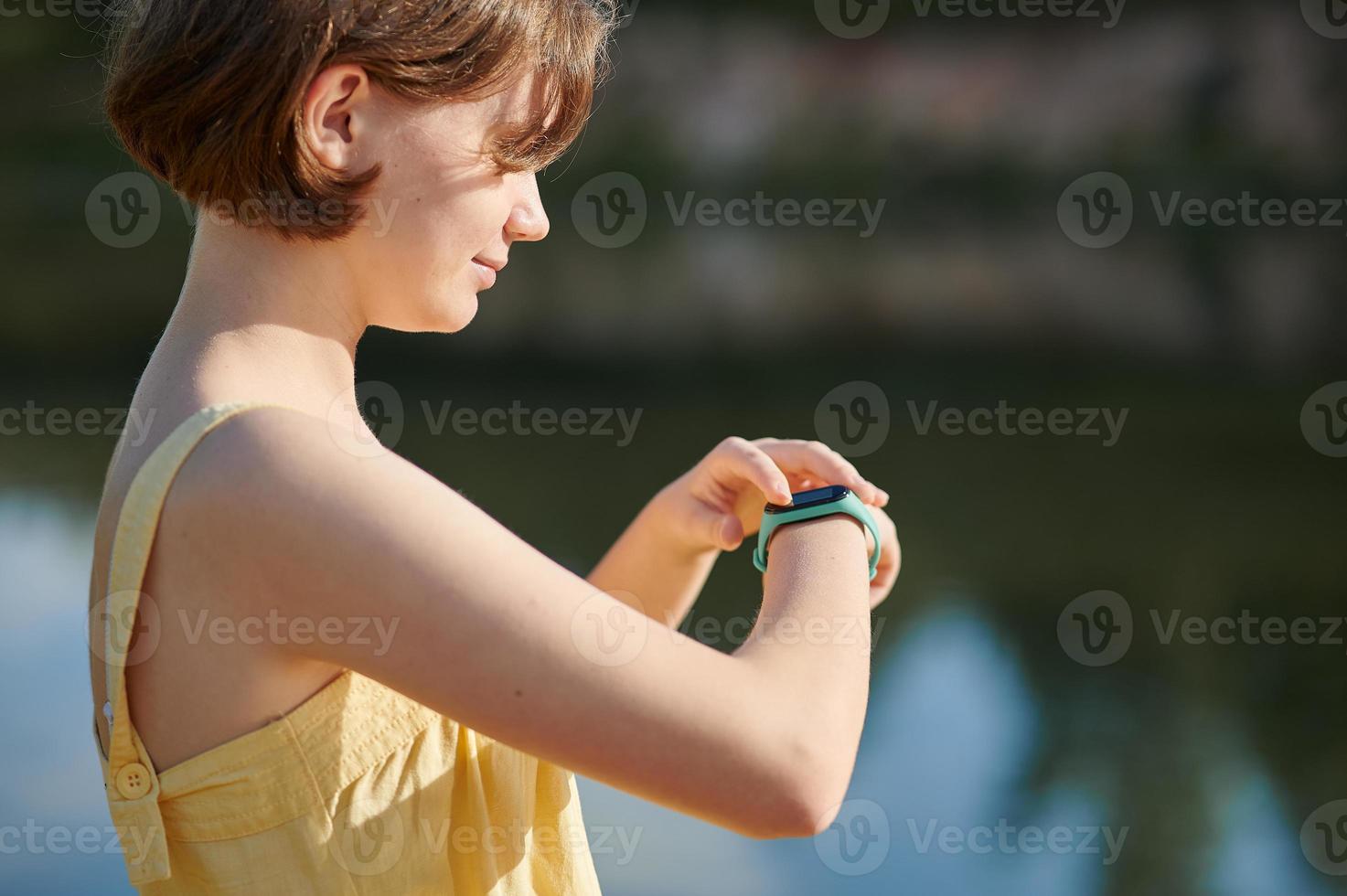 A teenage girl sets up a fitness tracker. Walking tour. photo