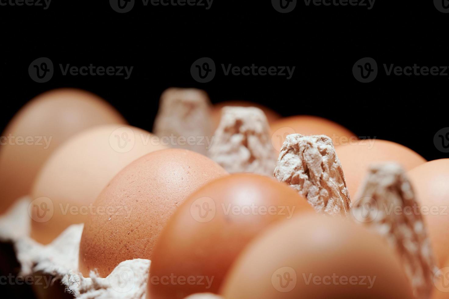 Eggs close up in egg protective container on black background. Foreground and background in blur. Focus in the center. photo