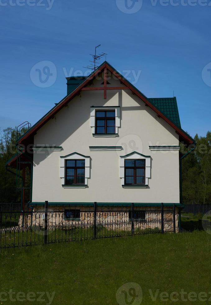 Country house and a green manicured lawn in front of the house. photo