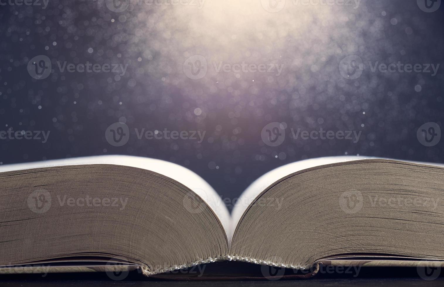 Open book illuminated by light side view close-up on a gray background. The background in blur. Photo with copy space.