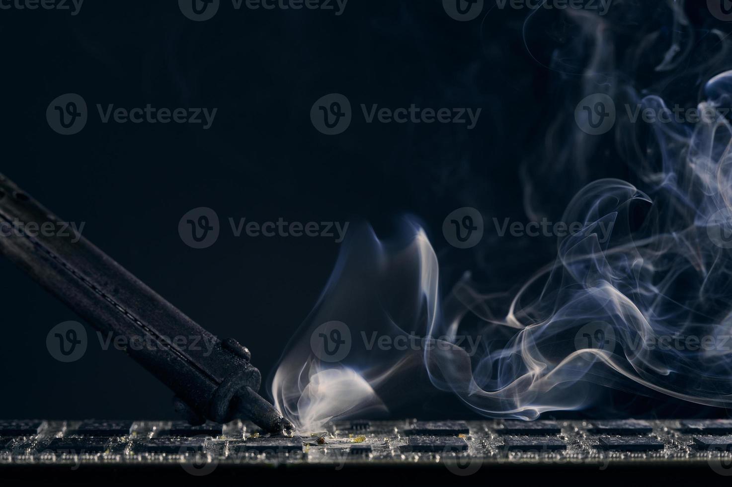 Backdrop of smoking soldering iron on dark background. photo