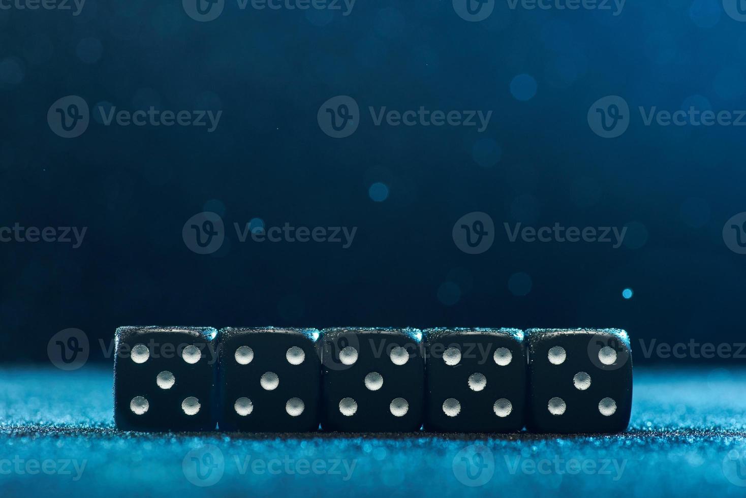 Game cubes are next to each other. Five identical black cubes on blue background. Photo with bokeh.
