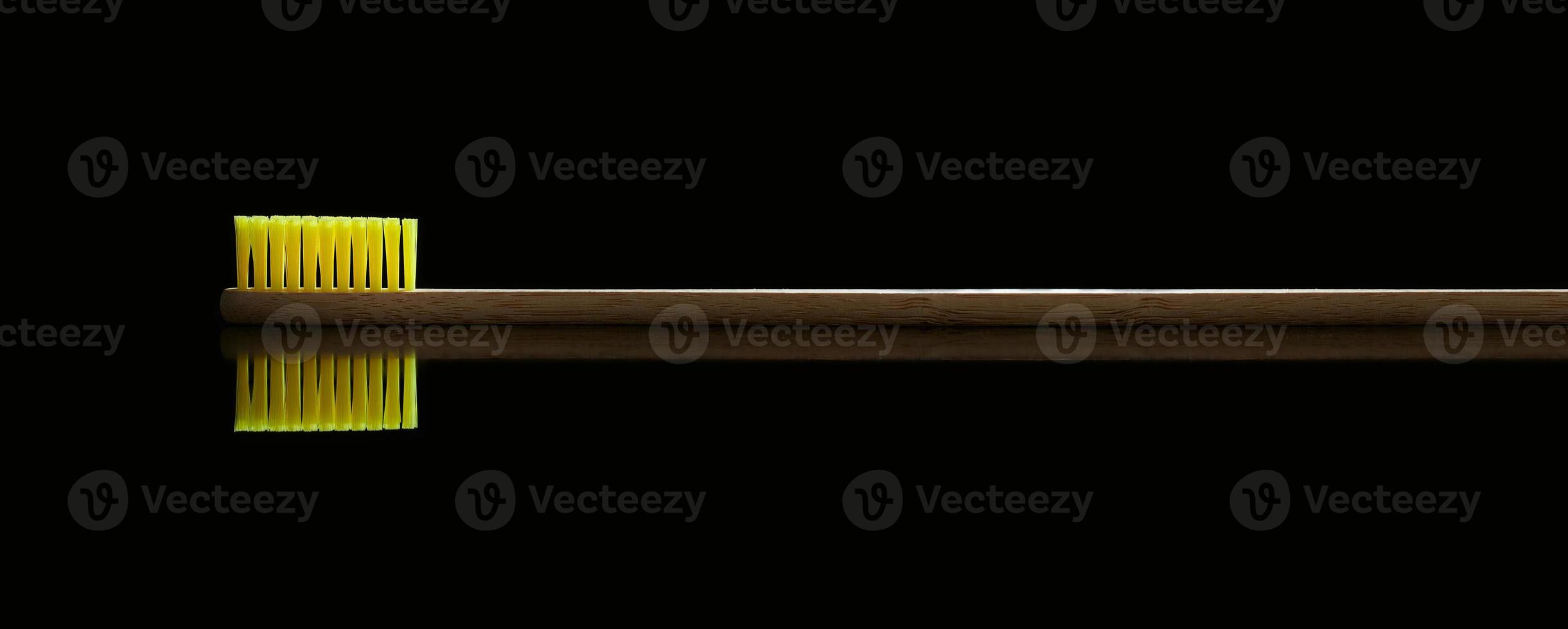 Natural bamboo toothbrush with reflection on black isolated background. Oral care and dental health. Photo with copy space.