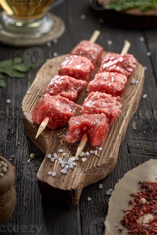 carne fresca cruda en brochetas en una tabla de cortar de madera. kebab crudo. foto