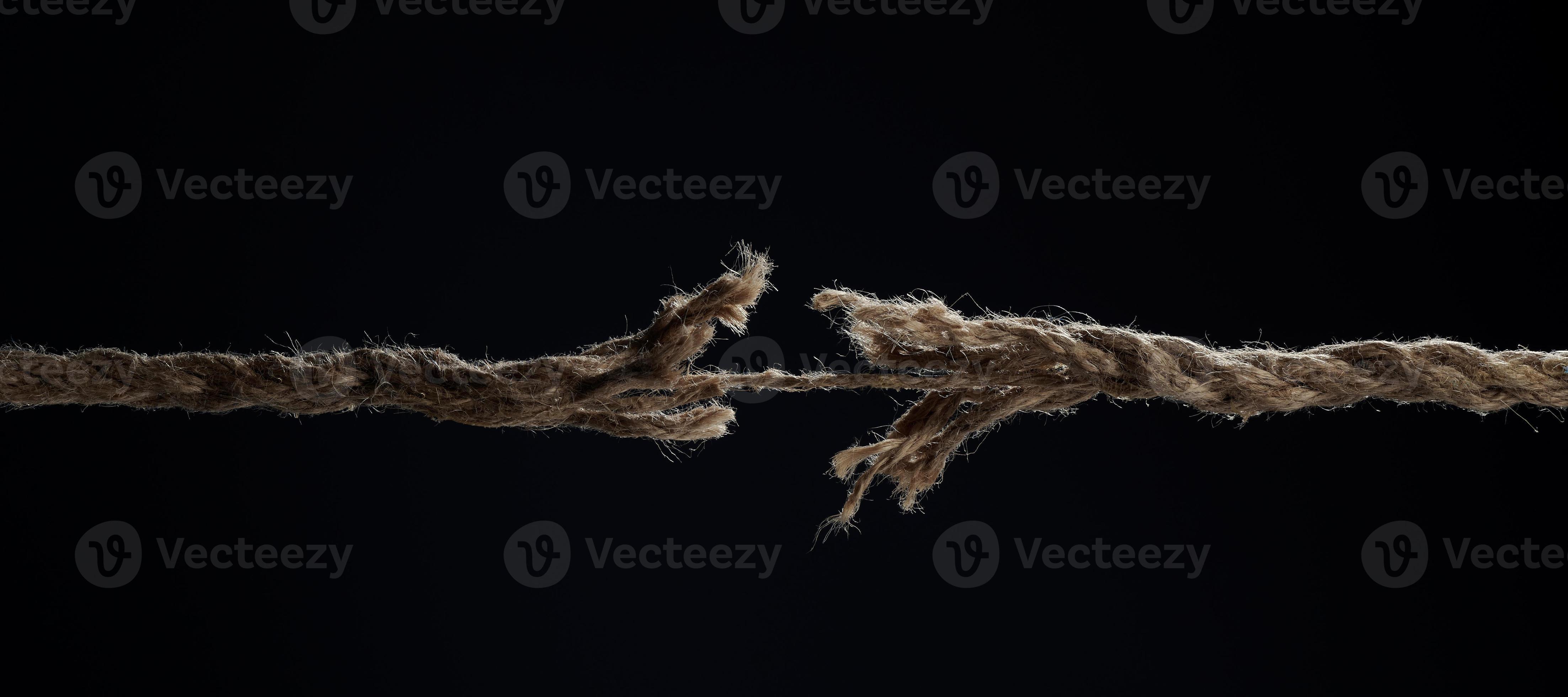 A stretched rope breaks on a black background. The concept of divorce