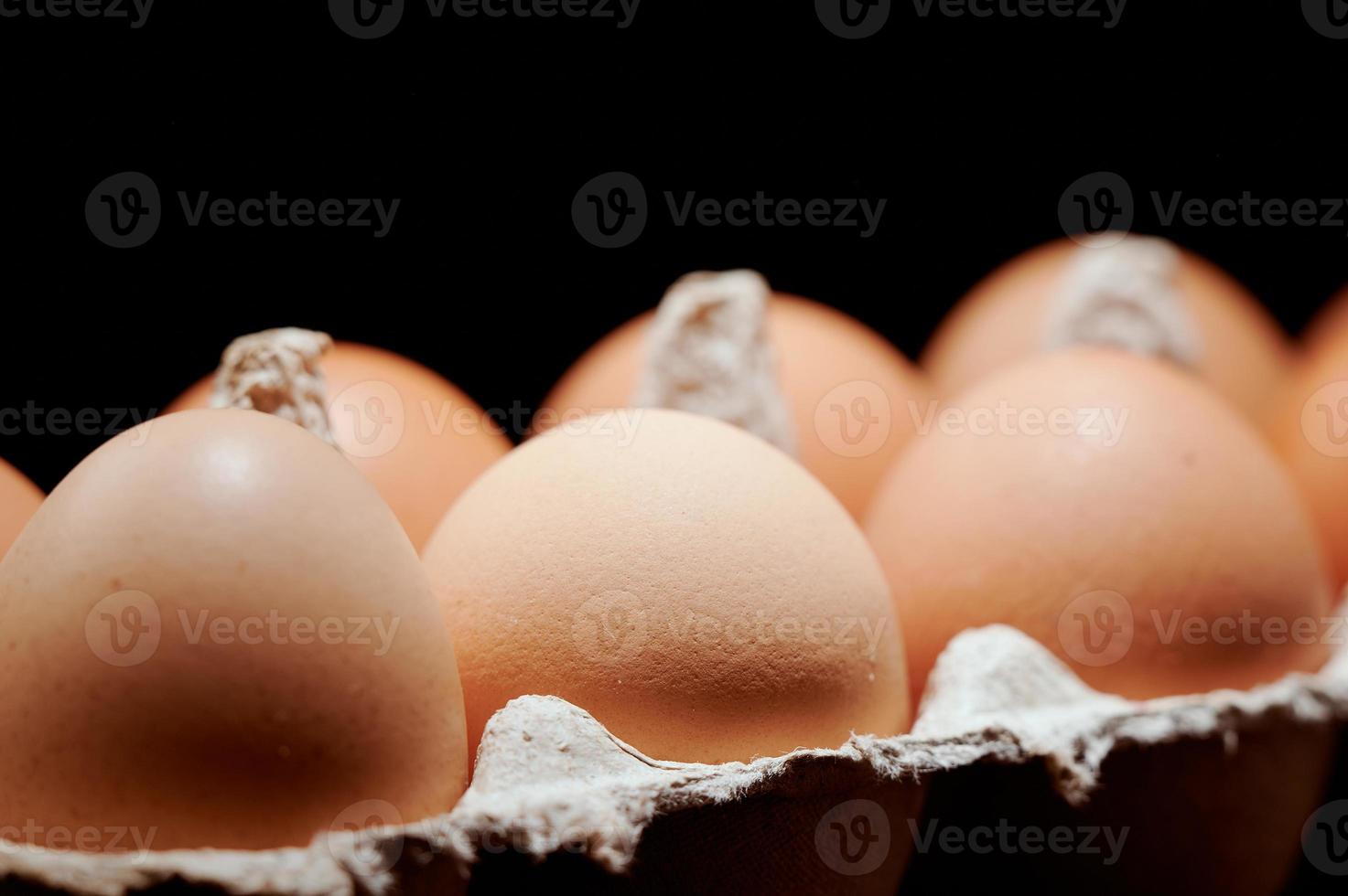 Eggs close up in egg protective container on black background. Foreground and background in blur. Focus in the center. photo