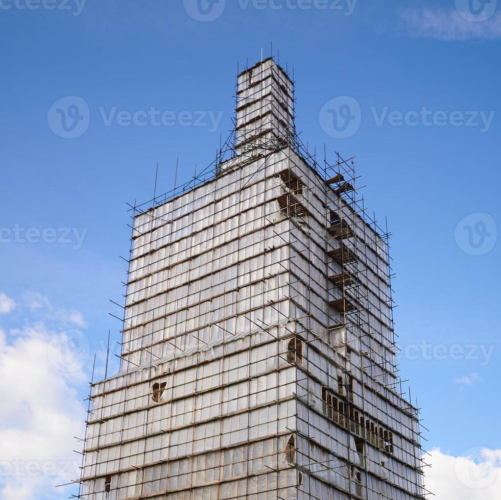 Scaffolding from planks around old bell tower. Concept of historical reenactment of repair work, access to elements of buildings of complex configuration. photo