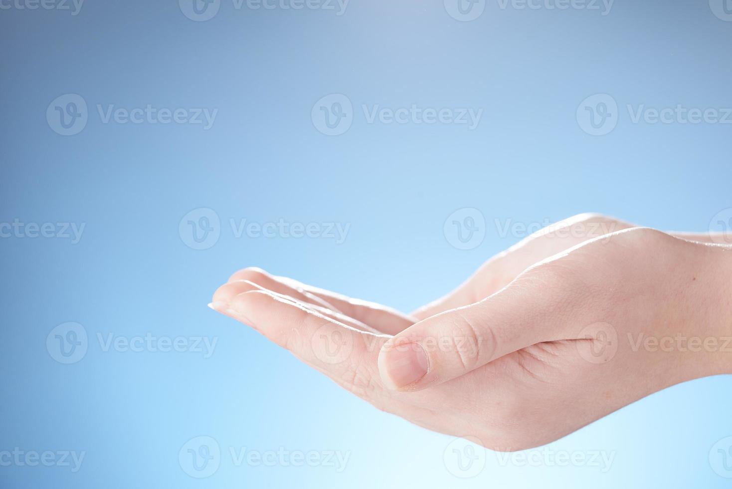 Close-up of beautiful woman's hands, palms up. Isolated on blue background. Photo from copy space.