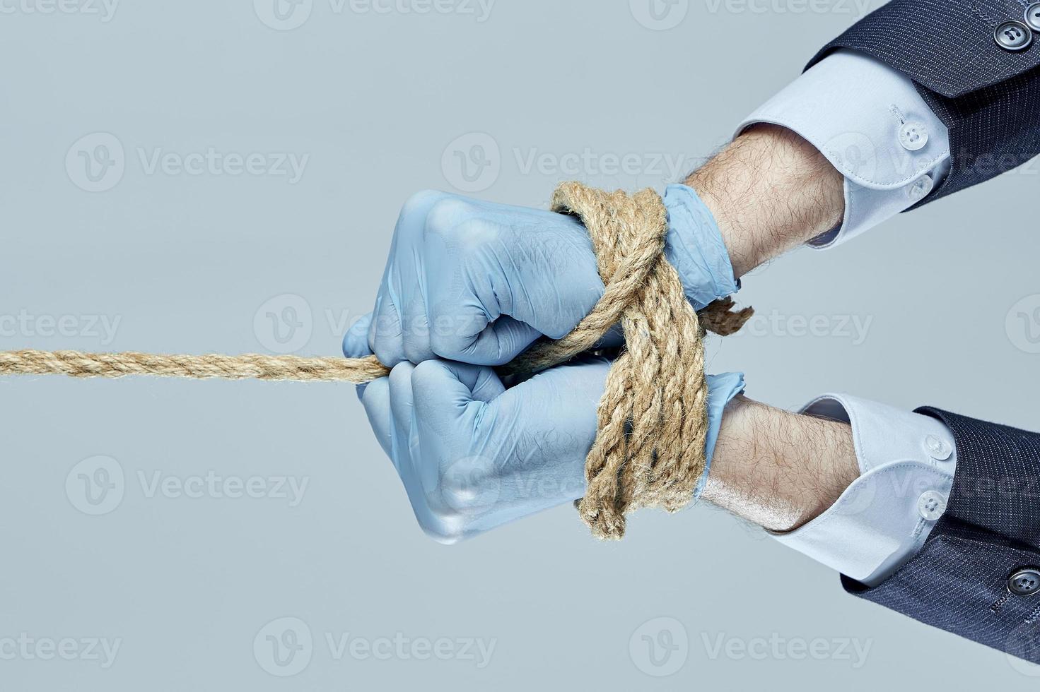 Business man pulling and bond tied with rope. Concept business hands are tied with a rope. Concept business hands are tied by ban on work. photo