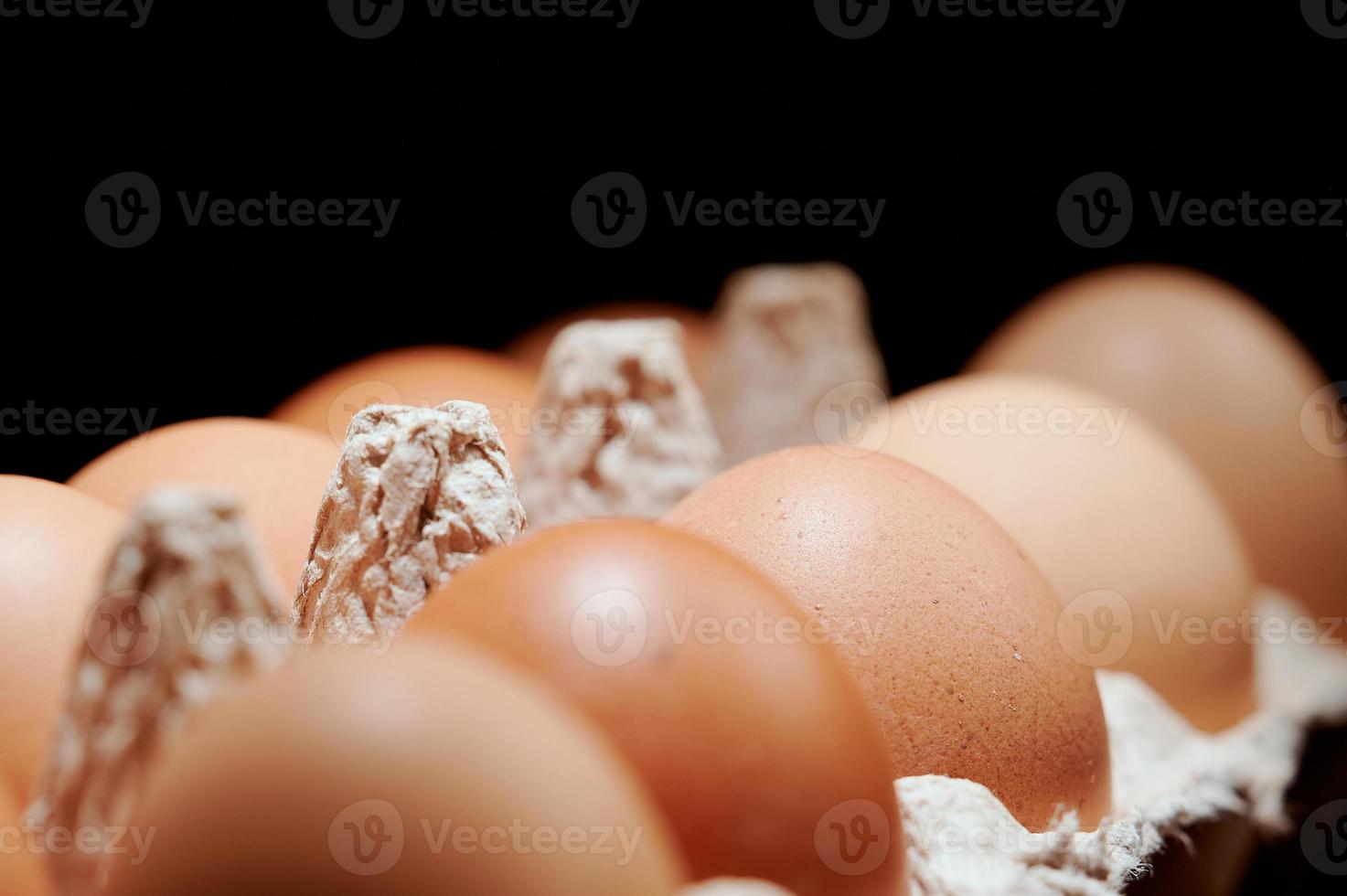 Eggs in a protective container on black background. Foreground and background in blur. photo