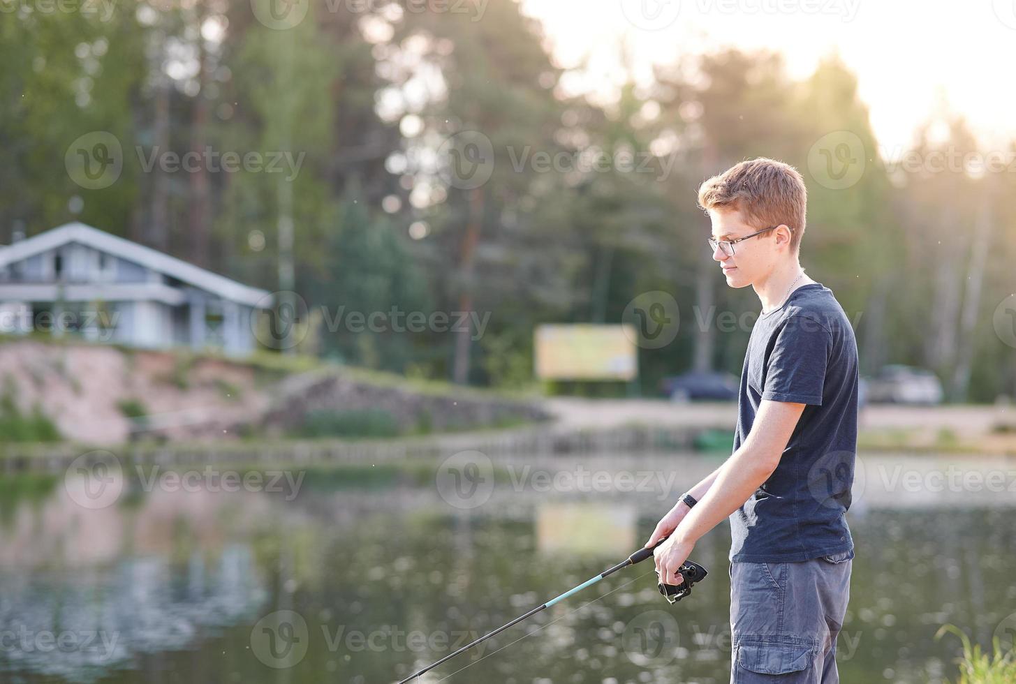 Young guy fishing on Lake with rod . Travel Lifestyle concept summer vacations. Paid fishing. photo
