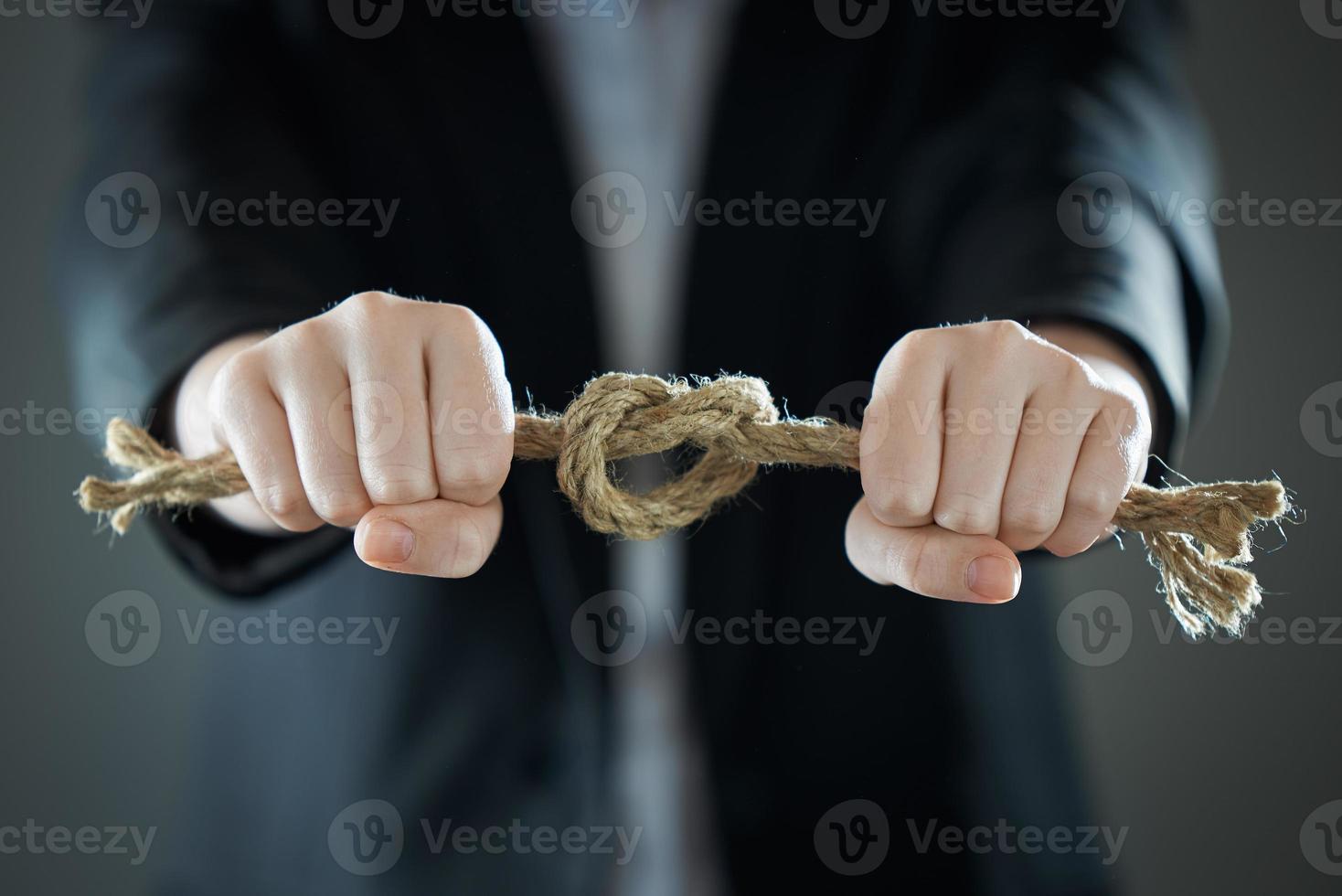 The businessman's hands tighten the rope knot against background of suit in blur. photo