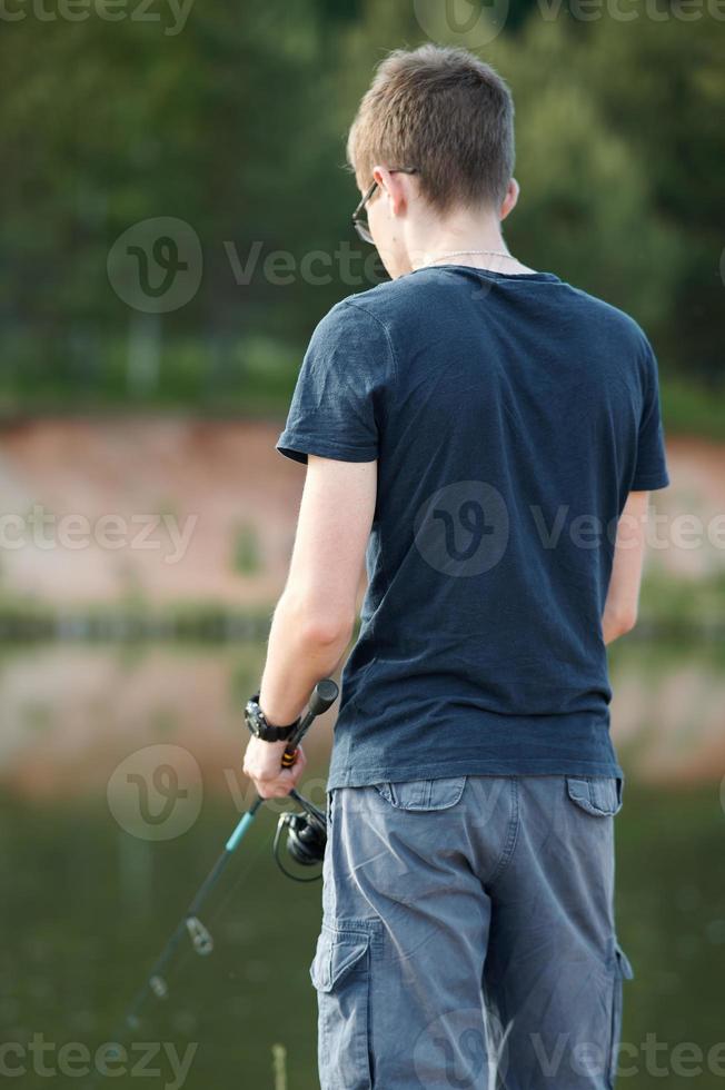 joven pescando en el lago con caña. concepto de estilo de vida de viaje vacaciones de verano. foto