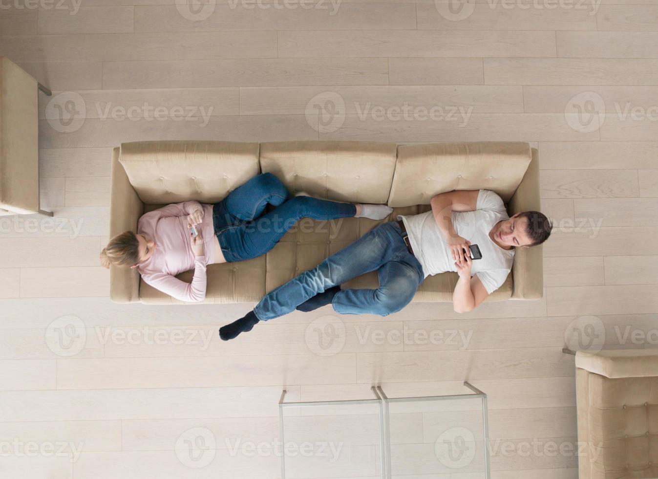 couple on sofa using mobile phones top view photo