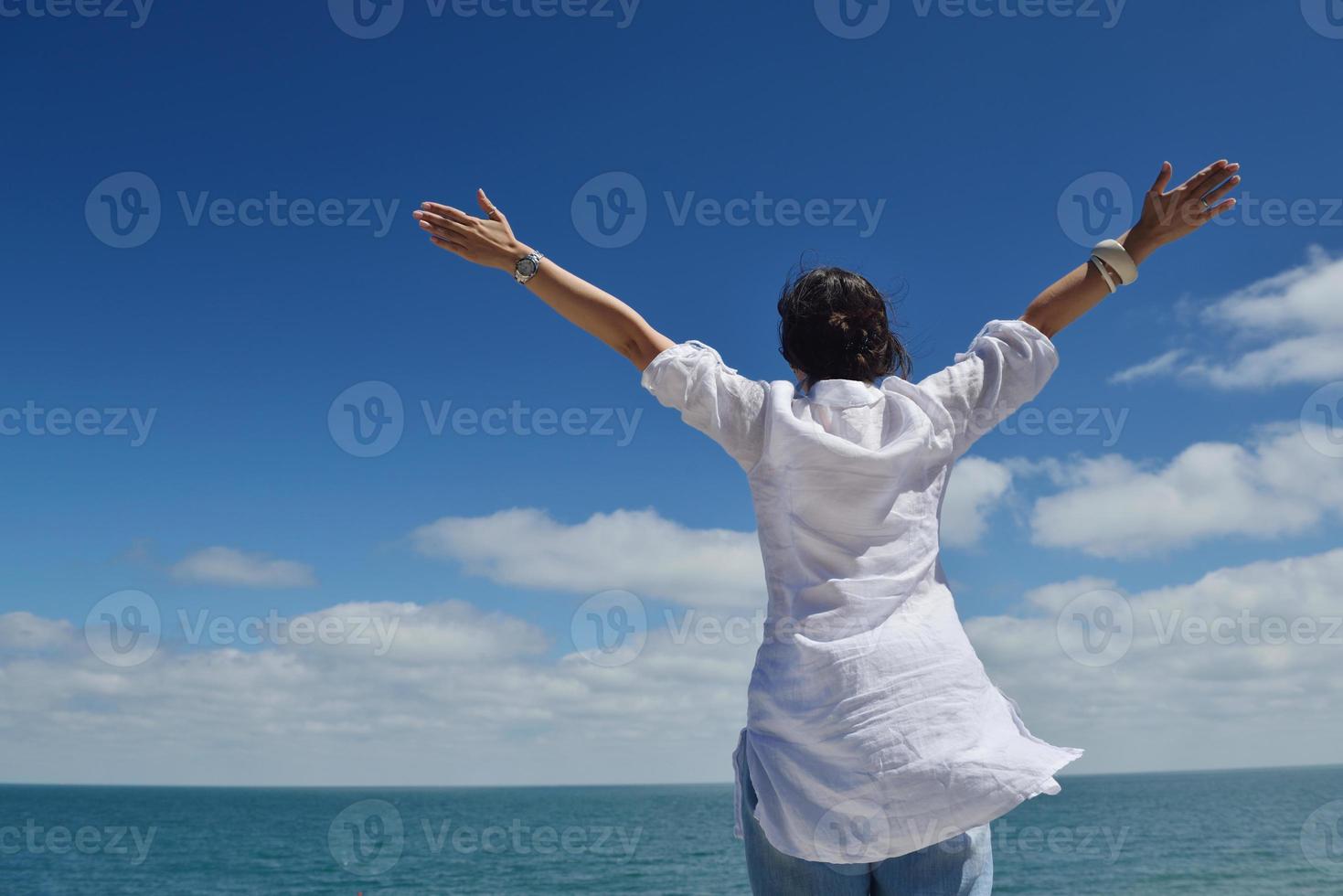 mujer joven feliz con los brazos extendidos al cielo foto