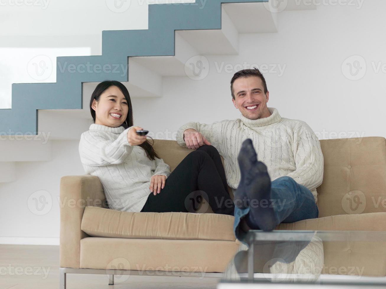 multiethnic couple on the sofa watching television photo