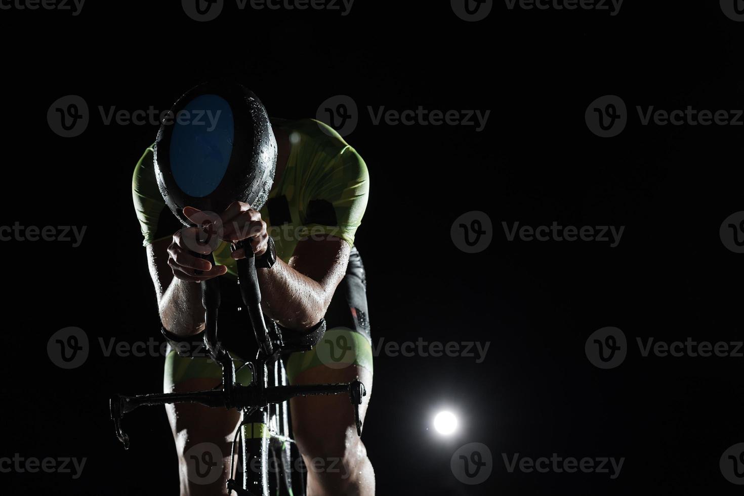 atleta de triatlón montando bicicleta rápido por la noche foto