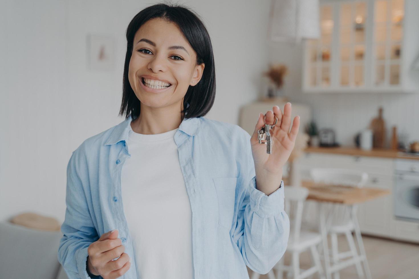 Smiling woman showing holding keys to new house. Real estate sale, rental. Mortgage advertisement photo
