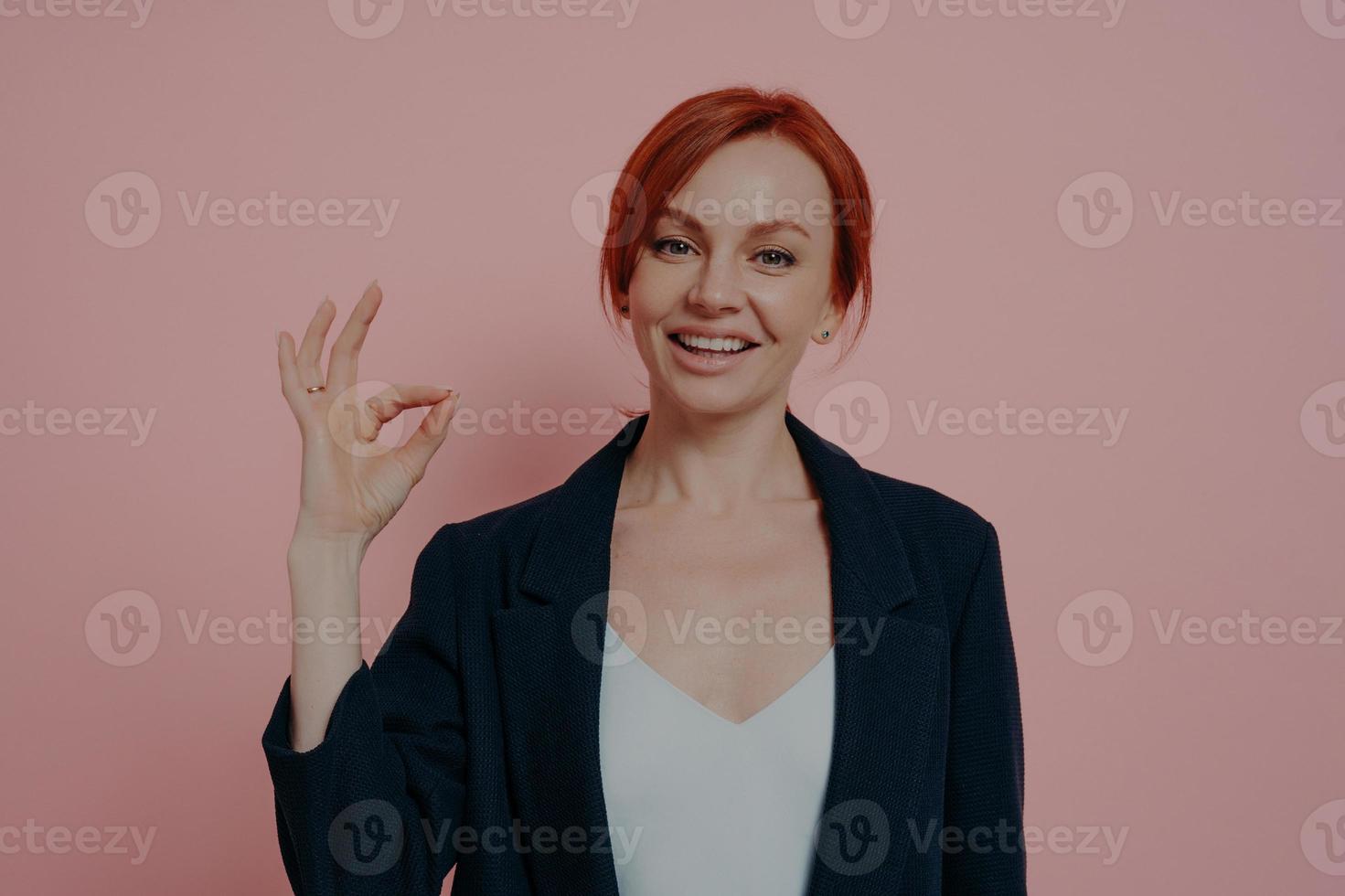 Headshot of young happy sitisfied business woman being sitisfied with choice, showing ok sign photo