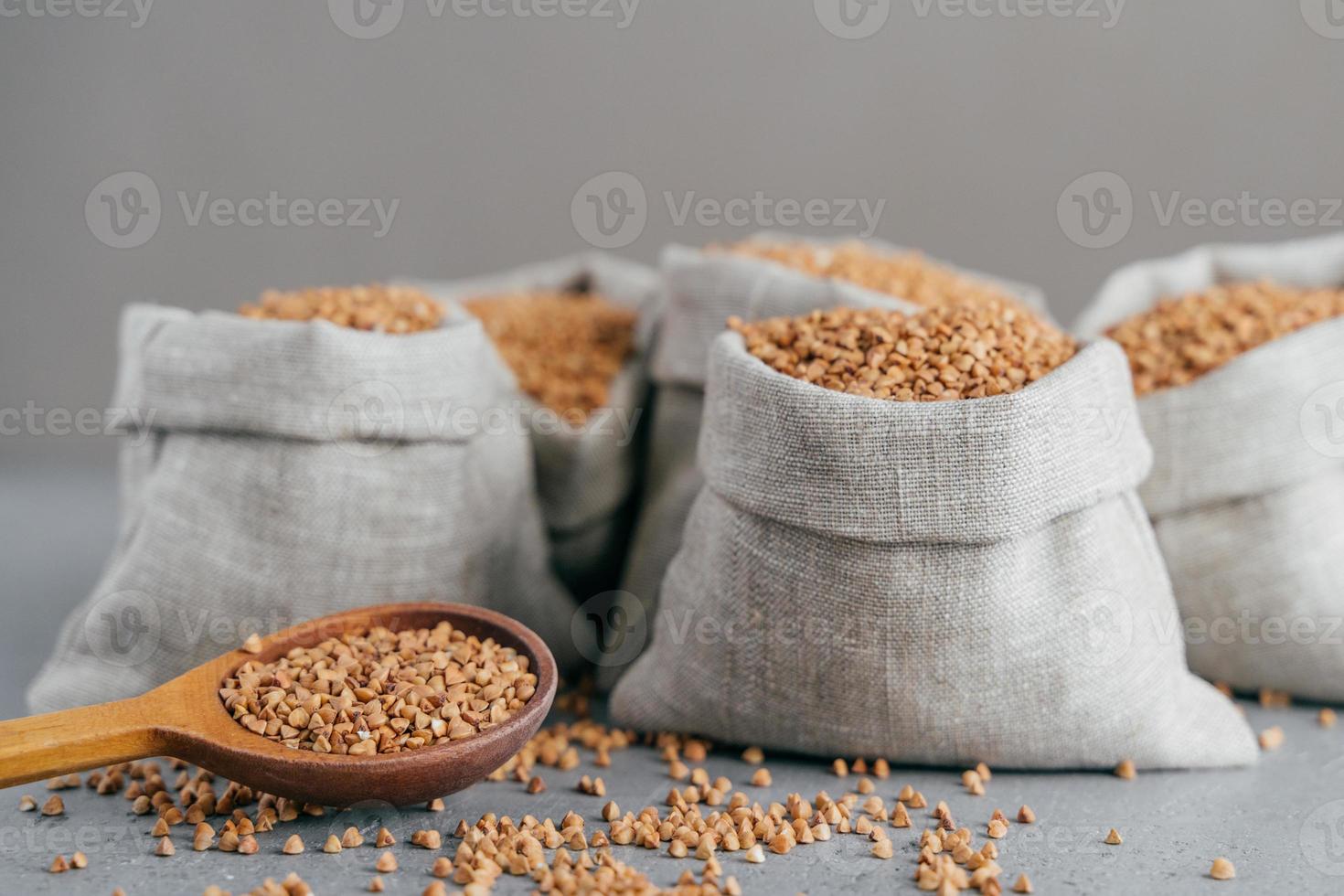 Dieting and nutrition concept. Brown buckwheat harvested in bags, isolated over grey background. Dry cereals ready for cooking photo