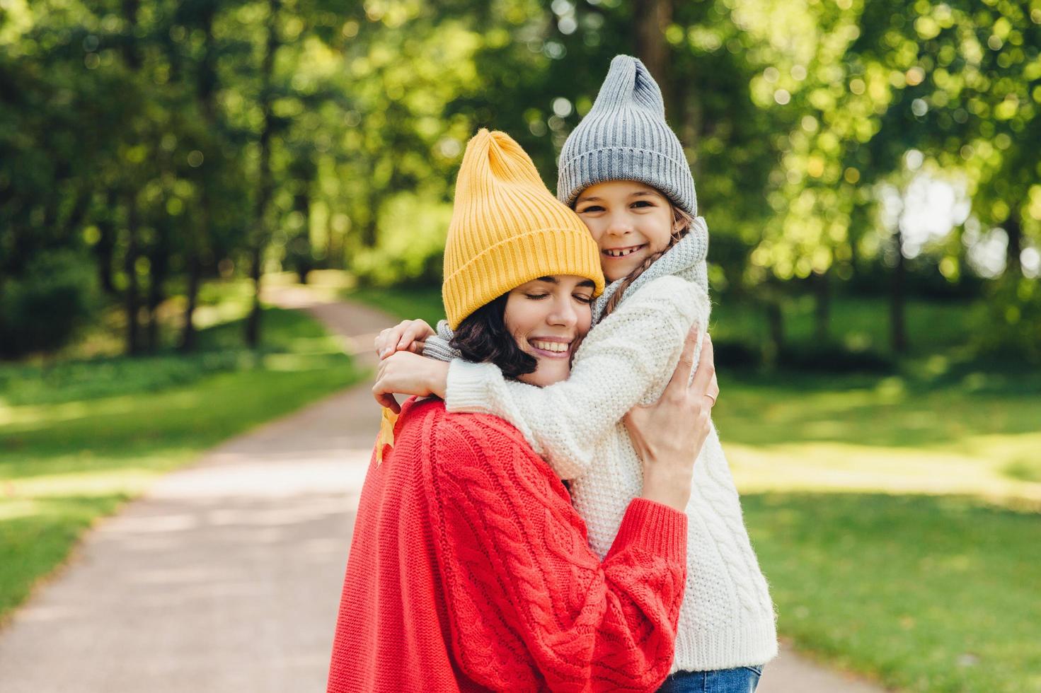 Affectionate good looking young mother embraces her single daughter, have warm relationship, being glad to have so clever and beautiful girl, play together outdoor, understand each other very well photo