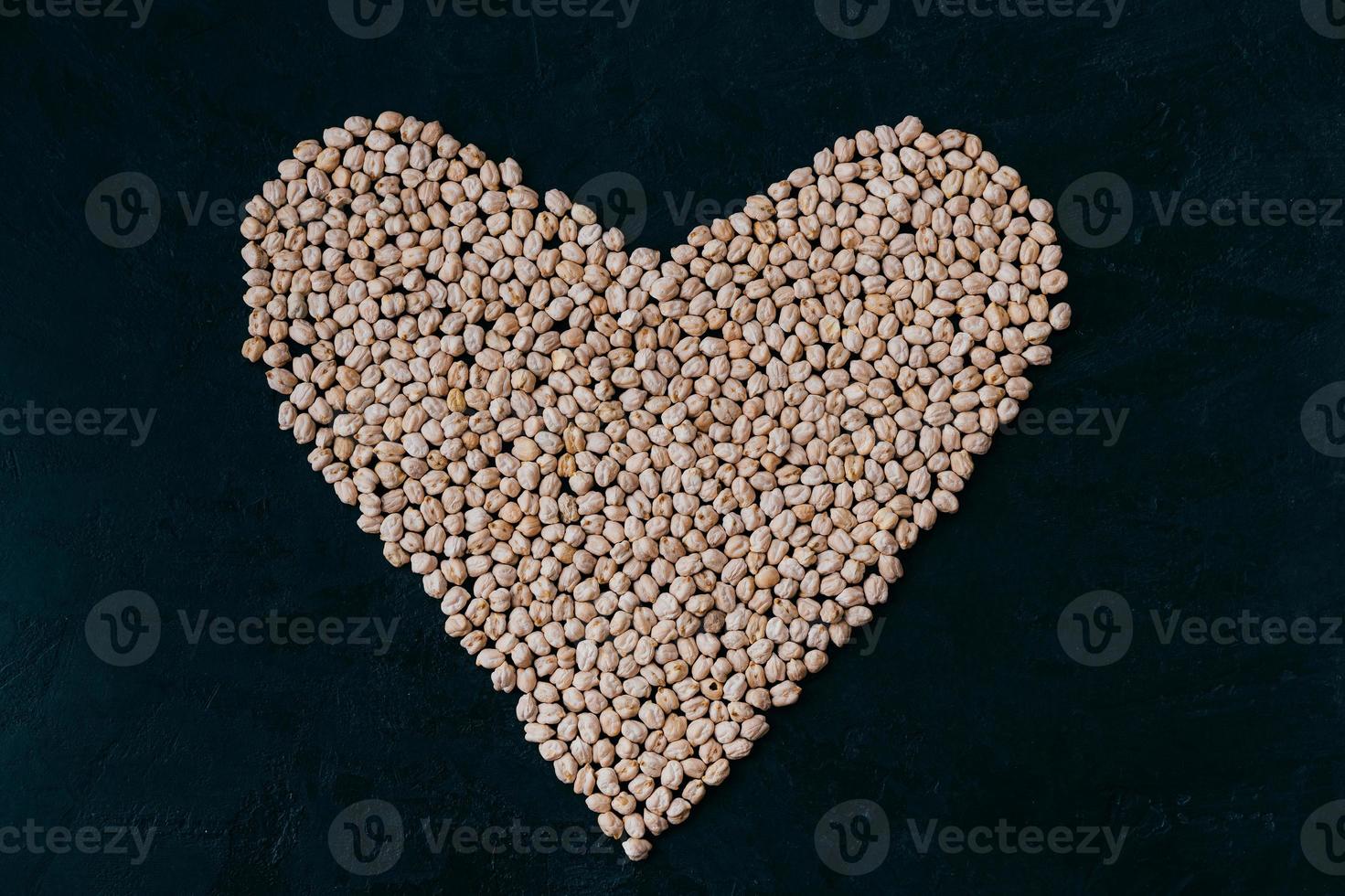 garbanzos crudos en forma de corazón aislado en fundamento negro. cultivo orgánico. proteína cruda ingrediente vegano saludable. comida nutritiva. garbanzos crudos foto