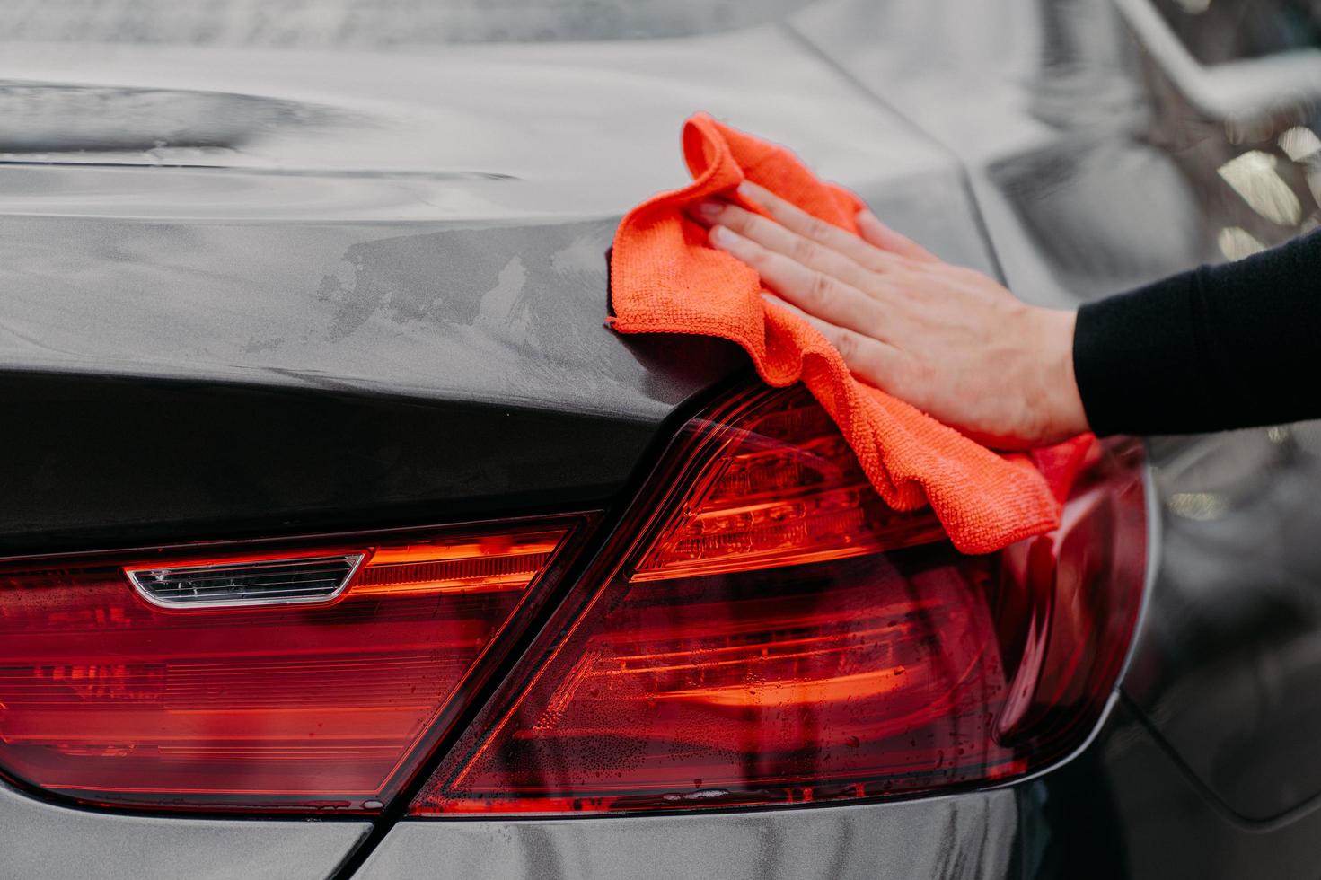 Cleaning auto concept. Mans hand wiping car hood with microfiber cloth. Unrecognizable man polishes vehicle. Detailing or valeting photo