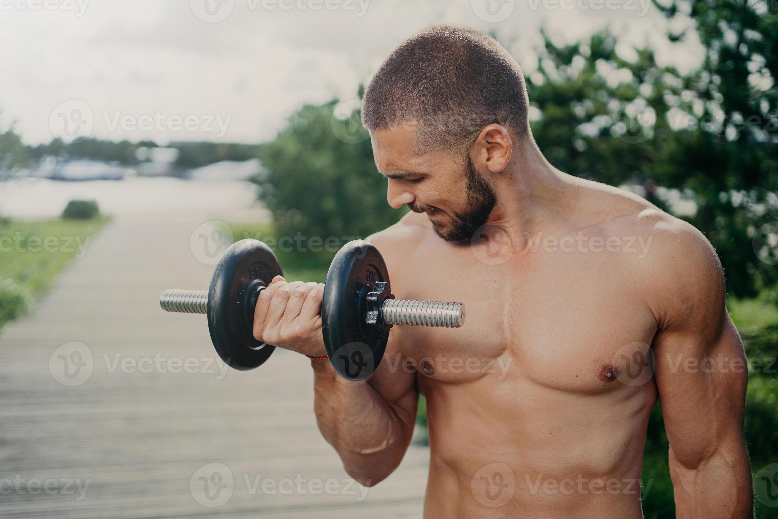 tiro al aire libre de un hombre musculoso fuerte con el torso desnudo levanta pesas pesadas y