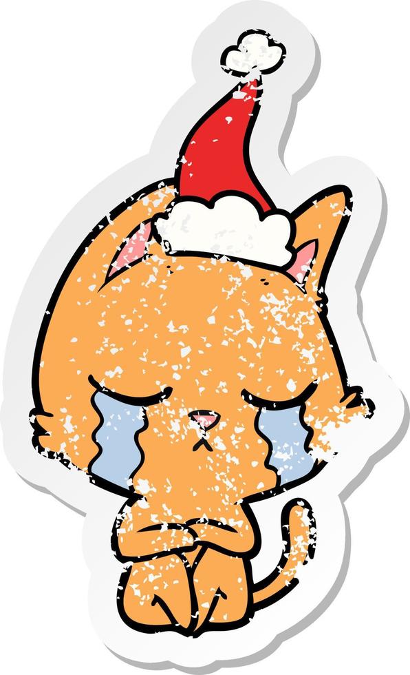 crying distressed sticker cartoon of a cat sitting wearing santa hat vector