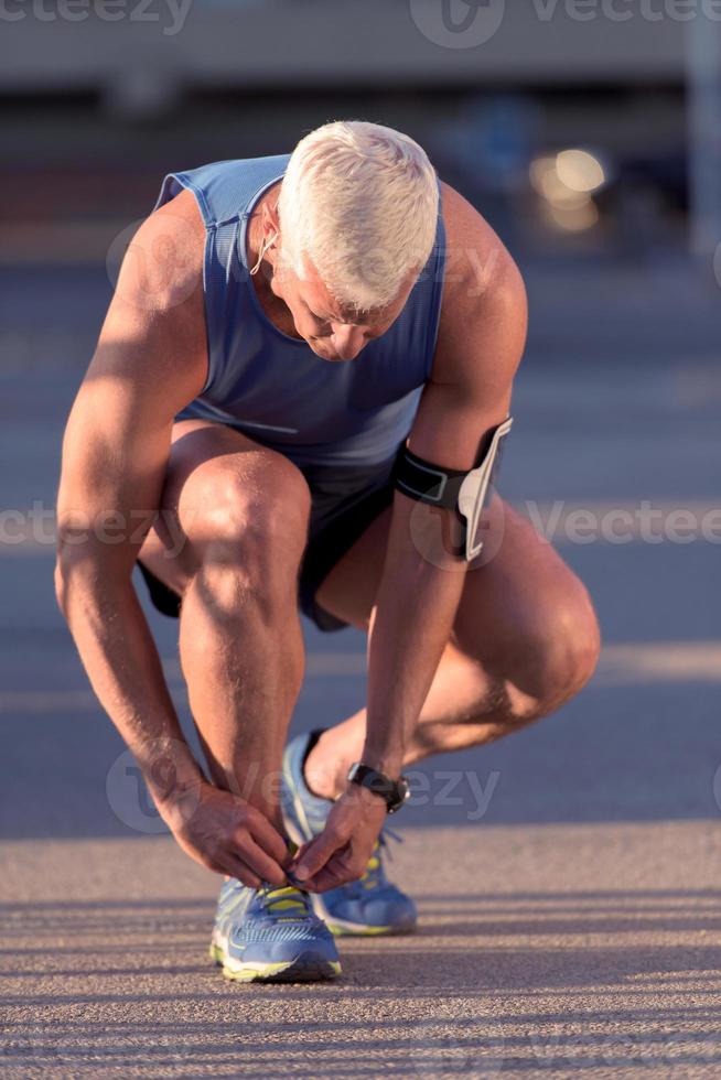 hombre atándose los cordones de las zapatillas foto