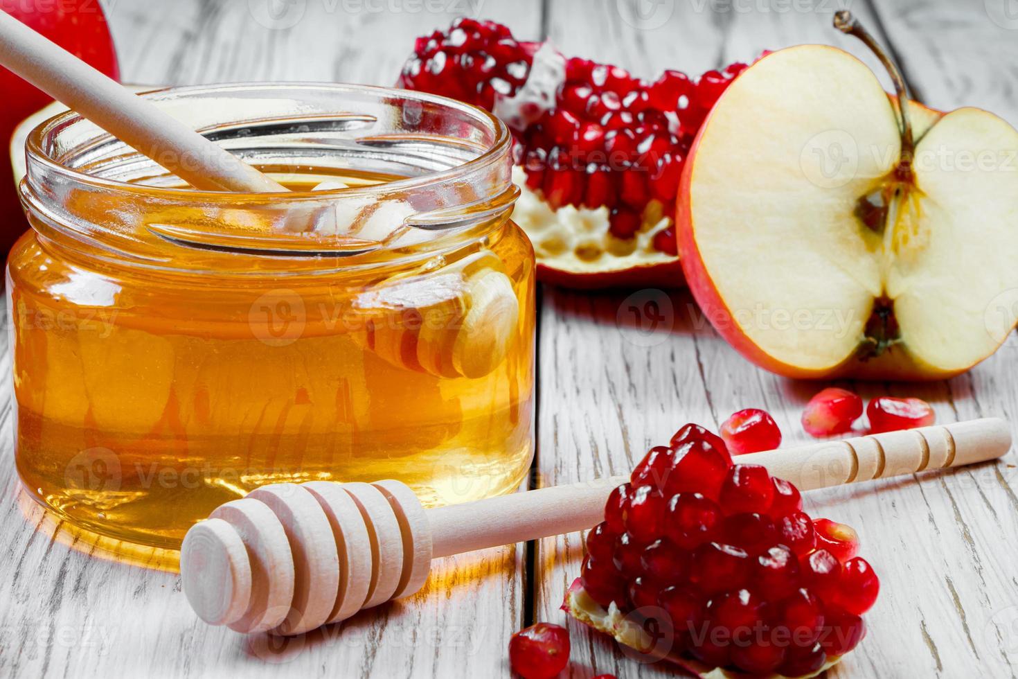 Jar with honey, apples and pomegranates on white wooden background. Happy Rosh Hashanah. Traditional symbols of Jewish New Year celebration. photo