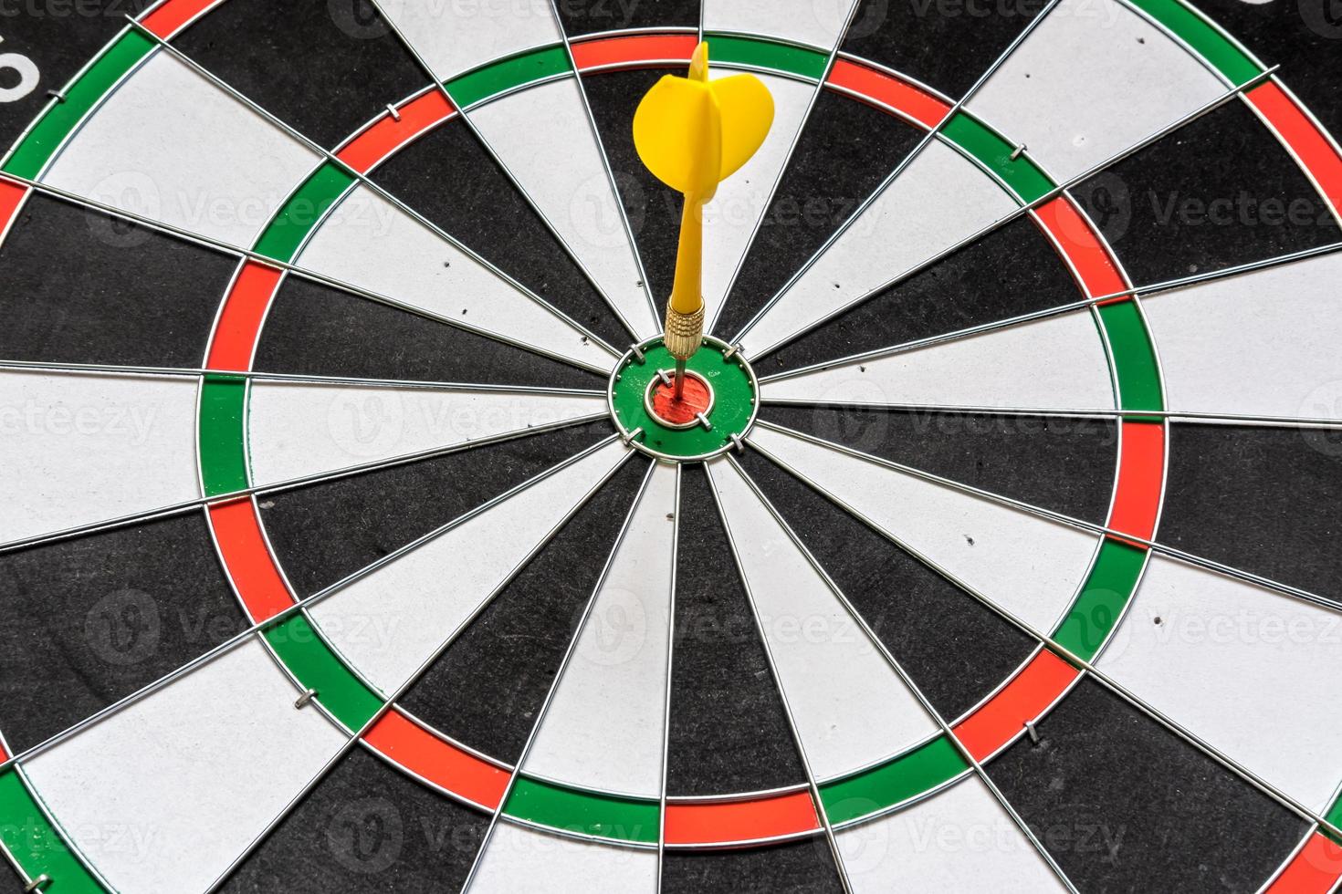 Red and yellow dart arrows hitting in the target center of dartboard. Success hitting target aim goal achievement concept photo