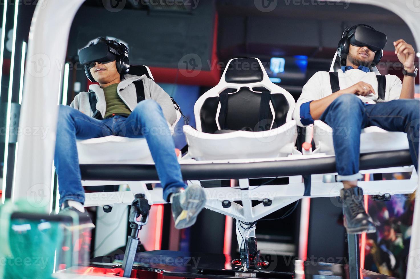 Two young indian people having fun with a new technology of a vr headset at virtual reality simulator. photo