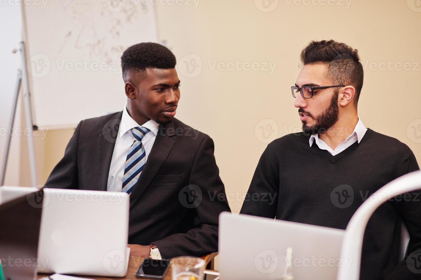 equipo de negocios multirracial que aborda la reunión alrededor de la mesa de juntas. hombre de negocios africano y árabe. foto