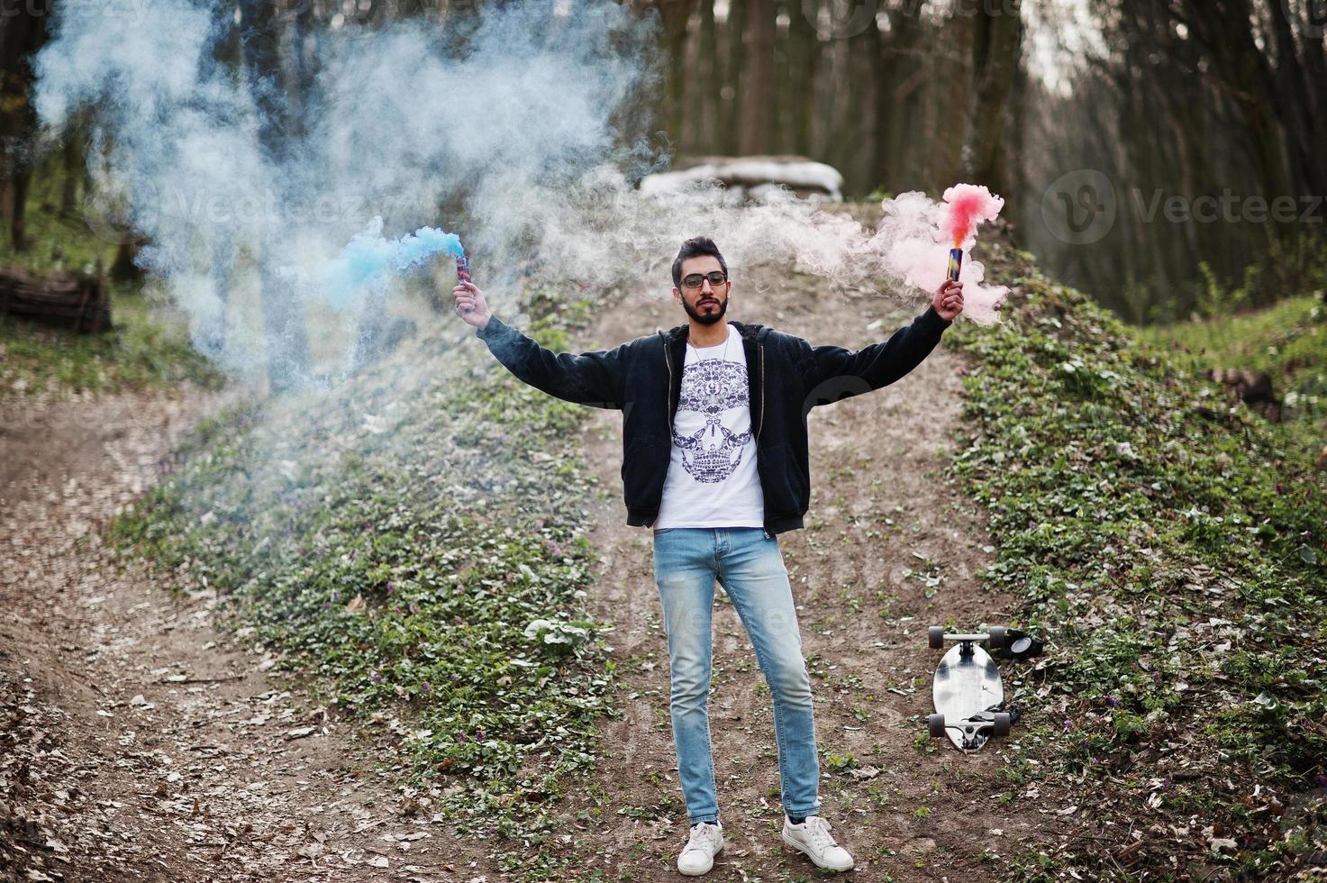 Street style arab man in eyeglasses hold hand flare with red and blue smoke grenade bomb. photo