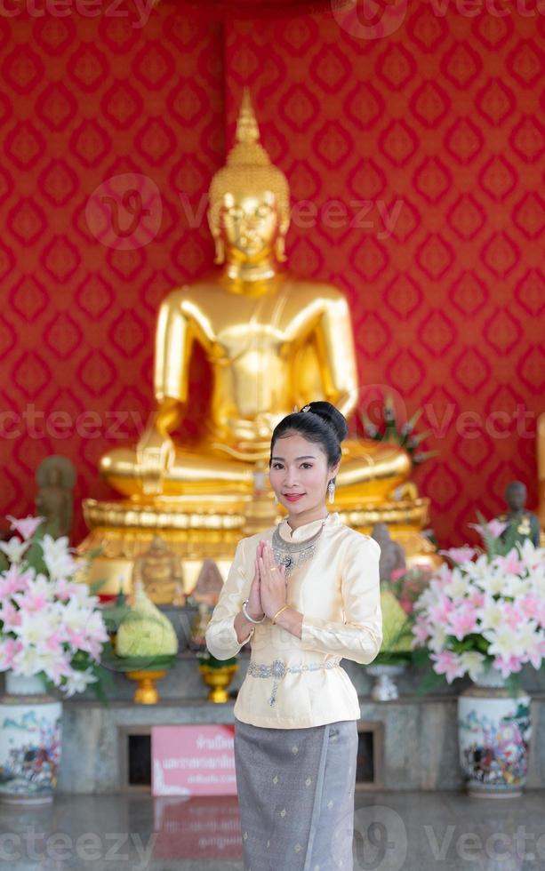 A woman wearing a Thai dress with a hand sign photo