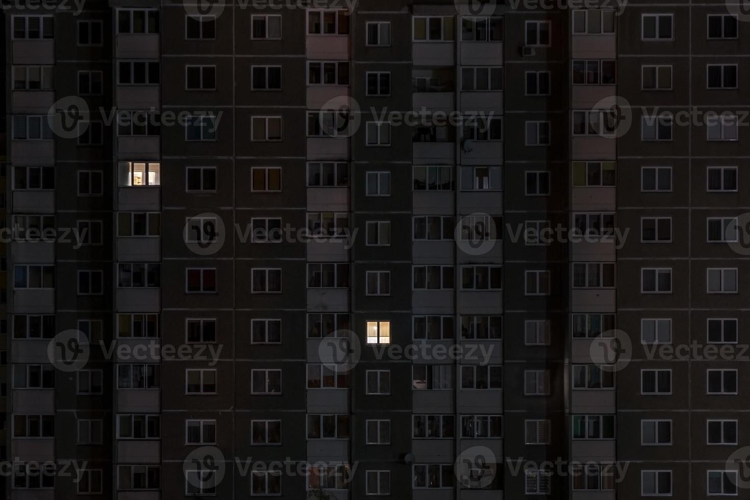 panorama nocturno plano de luz en ventanas de edificios de varios pisos. la vida en la gran ciudad. concepto para una pareja enamorada en aislamiento foto