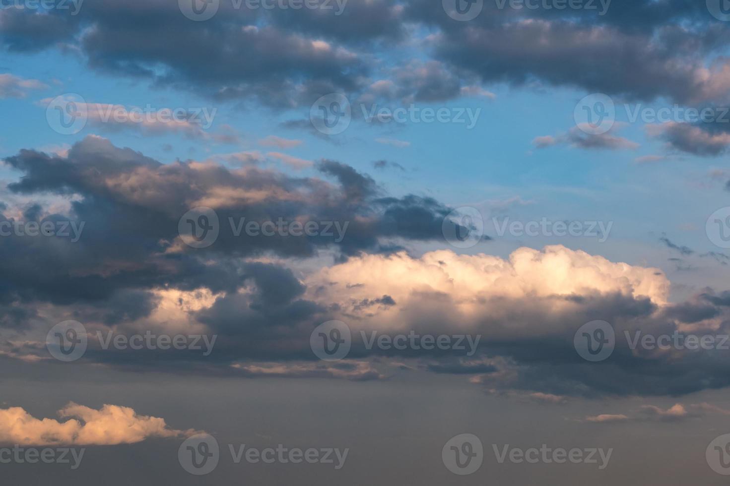 Blue sky background with evening fluffy curly rolling clouds. Good windy weather photo