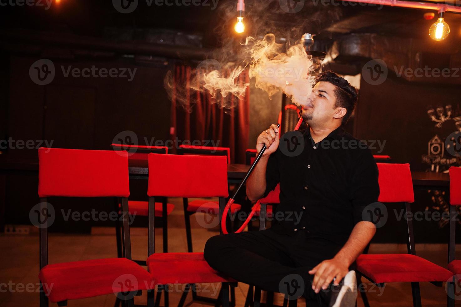 Asian man smoke hookah and having rest at lounge bar. photo