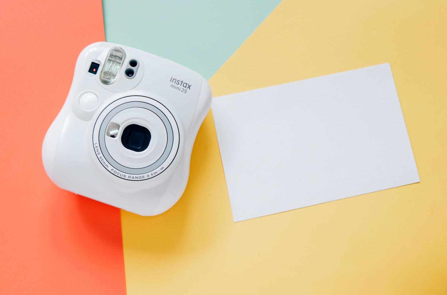 cámara instantánea con tarjeta de papel en blanco sobre fondo colorido moderno foto