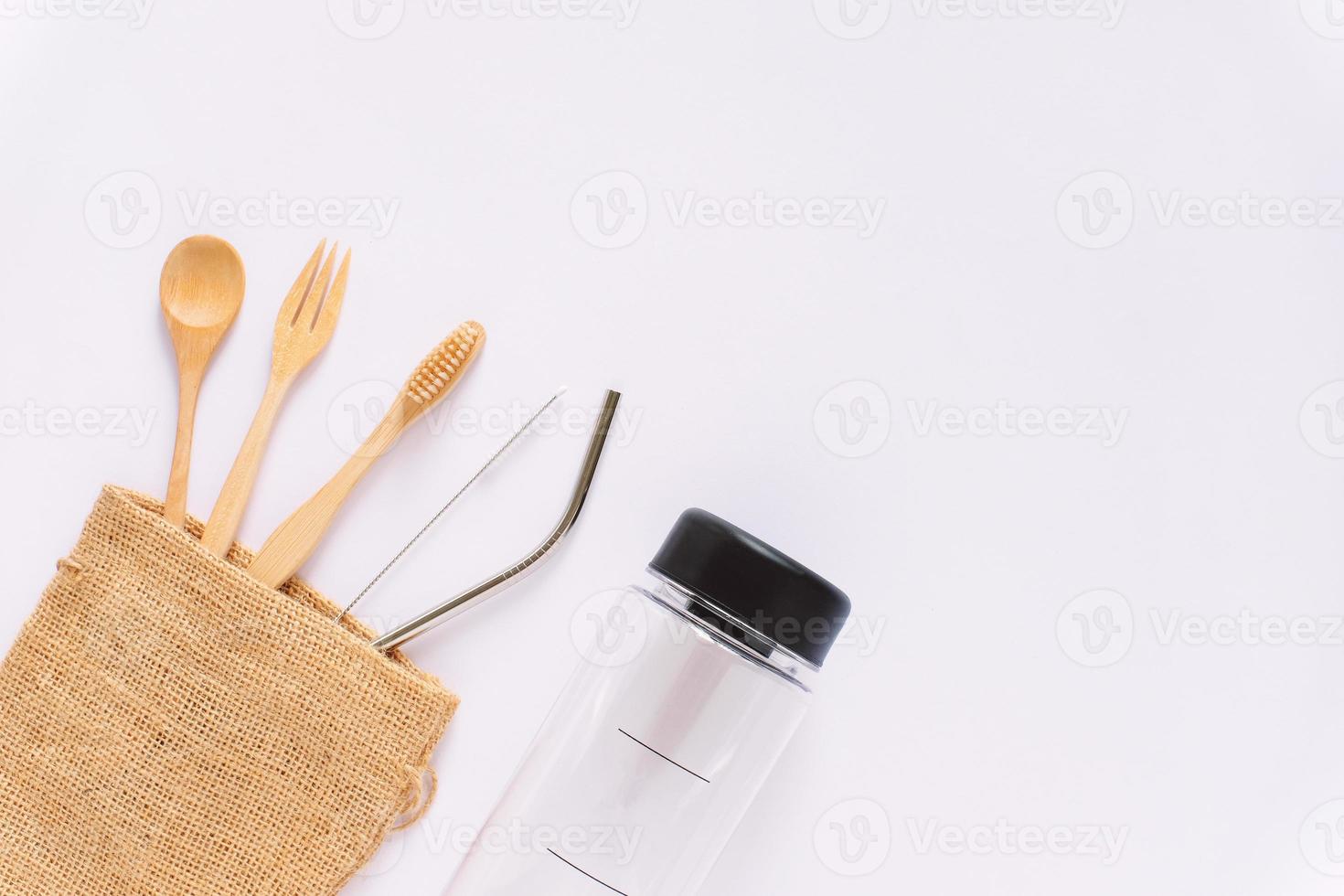 Flat lay of sustainable products, wooden spoon, stainless straw in sack bag with bottle on white background and copy space, eco friendly and zero waste concept photo